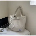 Detail of minimalist cream tote bag with round coin purse on a bed with lifestyle props - Off White