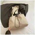Macro-opname van beige bucket bag met trekkoord, geplooide textuur en brede riem - Broken Wit