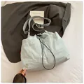 Dettaglio borsa a secchiello in nylon azzurro con chiusura a coulisse e logo in metallo - Blu