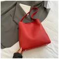 Dettaglio della borsa tote in pelle rossa con piedini protettivi argento sui vestiti - Rosso