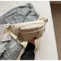 Detail of cream canvas belt bag with multiple zip pockets and knotted charm - With Ornament / Off White