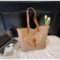 Dettaglio borsa tote in paglia con manici in pelle marrone e tasca frontale - Cachi