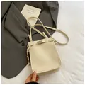 Chic beige lychee leather bucket bag featuring a secure metal twist lock and thin strap - White
