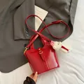 Elegante borsa a secchiello rossa con finiture dorate e ciondolo a forma di orsetto - Rosso