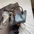 Borsa a secchiello in denim azzurro con manico in pelle marrone e logo in metallo dorato - Blu