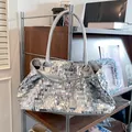 Dettaglio di una borsa tote in paillettes argento con tracolla lunga su supporto metallico - Argento