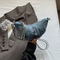Chic blue denim croissant bag featuring silver butterfly studs and knotted shoulder strap - Denim Blue