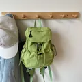 Light green nylon drawstring mini backpack with carabiner detail on a wooden wall hook - Green