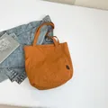 Burnt orange nylon tote bag with front pocket and shoulder straps on white background - Yellow
