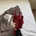 Borsa a secchiello rossa minimalista in pelle sintetica lucida con ciondolo floreale - Rosso