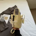 Borsa a secchiello beige in pelle con fiocco bianco e tracolla in set lifestyle - Giallo