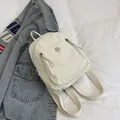 Minimalistischer cremeweißer Nylon-Mini-Rucksack mit Rundlogo und Vordertaschen-Detail - Weiß