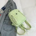 Minimalistischer mintgrüner Nylon-Rucksack mit Metall-Logo auf Denim-Hintergrund - Grün