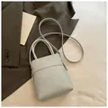 Minimalist light blue mini bucket bag with gold lettering on a dark suit - Blue Without Charm