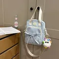 Light blue fabric crossbody bag with bow detail and plush charm on a door handle - With Charm / Blue