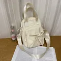 Chic cream canvas mini bag with a large bow and adjustable strap in a lifestyle setting - No Pendant / Off White