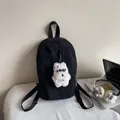 Minimalist black nylon backpack featuring a white plush puppy charm and laptop lifestyle setup - With Charm / Black