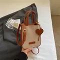 Bolso bandolera de lona con ribete de cuero marrón y colgante de corazón dorado - Marrón