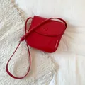 Detail of red patent leather crossbody bag with glossy finish and silver buckle strap - Red