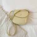Top-down view of light green glossy patent saddle bag with adjustable strap - Yellow