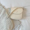 Detail view of cream saddle bag with adjustable strap and silver-tone hardware accents - White