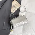 Silver woven cylindrical crossbody bag with gold metallic knot details on dark blazer - Silver