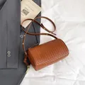 Brown woven leather cylinder crossbody bag with adjustable strap in minimalist style - Brown