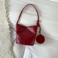 Minimalistische weinrote Leder-Eimertasche mit runder Münztasche und Knotengurt - Rot