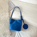 Minimalist royal blue suede bucket bag with decorative knotted straps and round charm - Blue