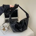 Bolso bandolera negro de media luna con correa ancha y textura suave en entorno de oficina - Negro