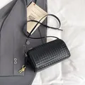 Minimalist black woven barrel crossbody bag with golden hardware and leather strap - Black