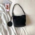 Minimalist black suede bucket bag with a round coin purse charm and stylish knot strap - Black