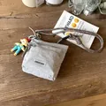 Borsa a secchiello in nylon grigio con doppia zip e tracolla intrecciata su un tavolo - Grigio