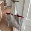 Nahaufnahme der silbernen Tragetasche mit rotem Innenfutter an einer weißen Tür - Tragetasche Und Kleiner Beutel / Silber Rotes Innenfutter