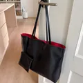 Gros plan du cabas en cuir noir avec doublure rouge et petite pochette suspendue - Sac Fourre-tout Et Petite Pochette / Noir Doublure Rouge