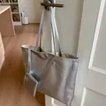 Detail der silbernen Metallic-Tote-Bag mit passender Tasche an einer weißen Tür - Tragetasche Und Kleiner Beutel / Silber Weißes Innenfutter