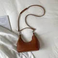 Close-up of brown woven texture on a minimalist crescent-shaped faux leather shoulder bag - Brown