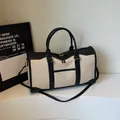 Beige canvas travel bag with black leather trim and adjustable shoulder strap - Black