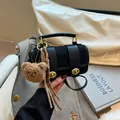 Bolso bandolera negro minimalista con herrajes dorados y llavero de oso de peluche - Negro