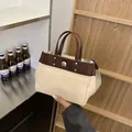 Bolso tote de lona y cuero marrón con tachuelas metálicas en un interior moderno - Sin colgante / Marrón