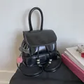 Detail of glossy black mini backpack featuring a cherry pendant and metallic drawstring beads - Black with Pendant
