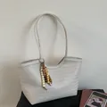 Détail du tissage en V et du gland en perles de bois sur ce sac fourre-tout tissé beige - Blanc avec pendentif