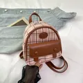 Pink plaid mini backpack in canvas and brown leather trim on denim jacket background - Pink