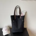 Bolso tote de lona negra con asas de cuero marrón y tachuelas metálicas decorativas - Negro