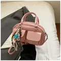 Pink glossy baguette bag with cute bear charm and adjustable strap shown on white bedding - Pink with Pendant
