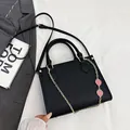 Borsa a spalla nera con trama litchi, catena dorata e ciondoli a fragola rosa - Nero
