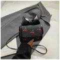 Mini black denim crossbody bag with red cherry embroidery and a large patent bow accent - Black