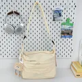 Große beige Nylon-Umhängetasche mit verstellbarem Riemen und Plüsch-Anhänger im Studio - Mit Anhänger / Gebrochenes Weiß
