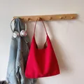 Detailed view of a red matte suede oversized hobo shoulder bag hanging on a wooden hook - Red