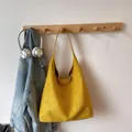 Close-up of mustard yellow suede tote bag hanging with high-quality matte finish - Yellow